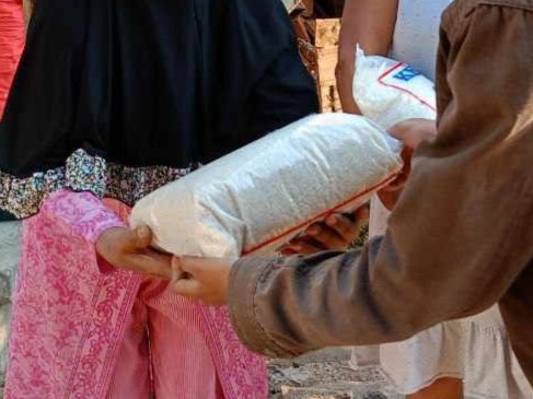 Satu kantong plastik berisi beras di dalam genggaman wanita tua